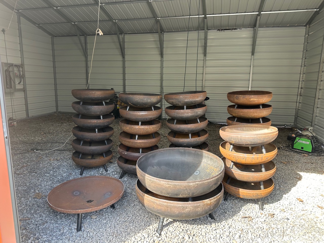 Finished steel fire pit bowls stacked in the Virginia fabrication shop