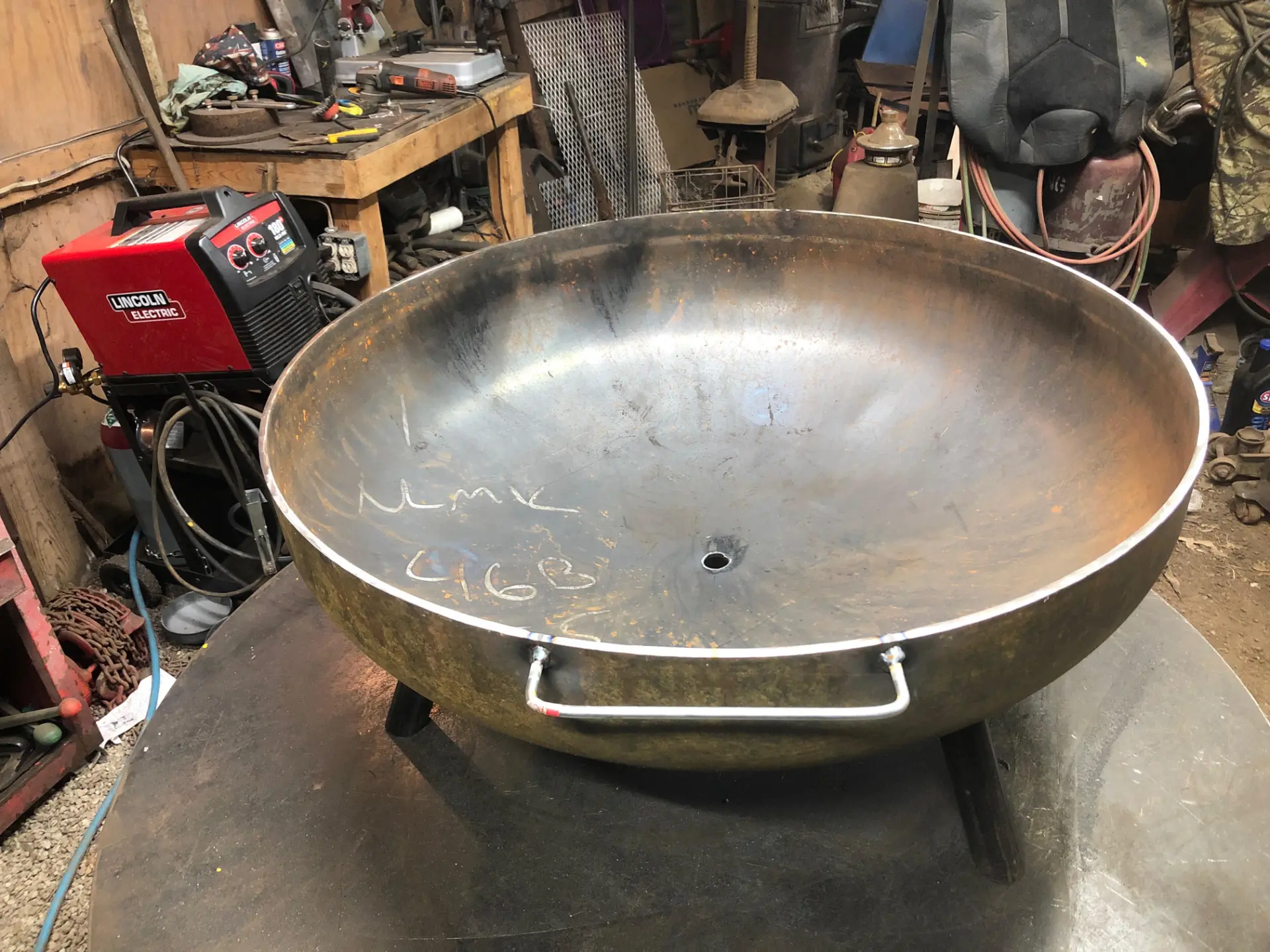 Steel fire pit with bent round-bar grab handles welded to the rim