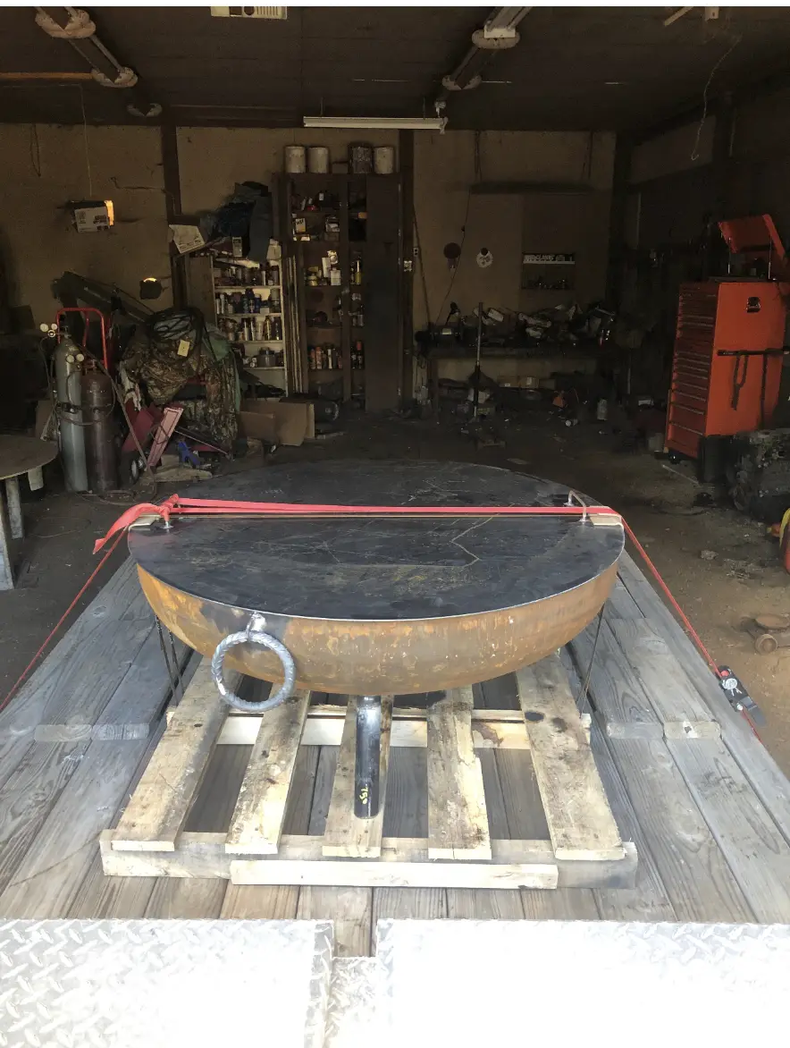 Heavy steel fire pit with a forged twisted lifting ring welded to the bowl